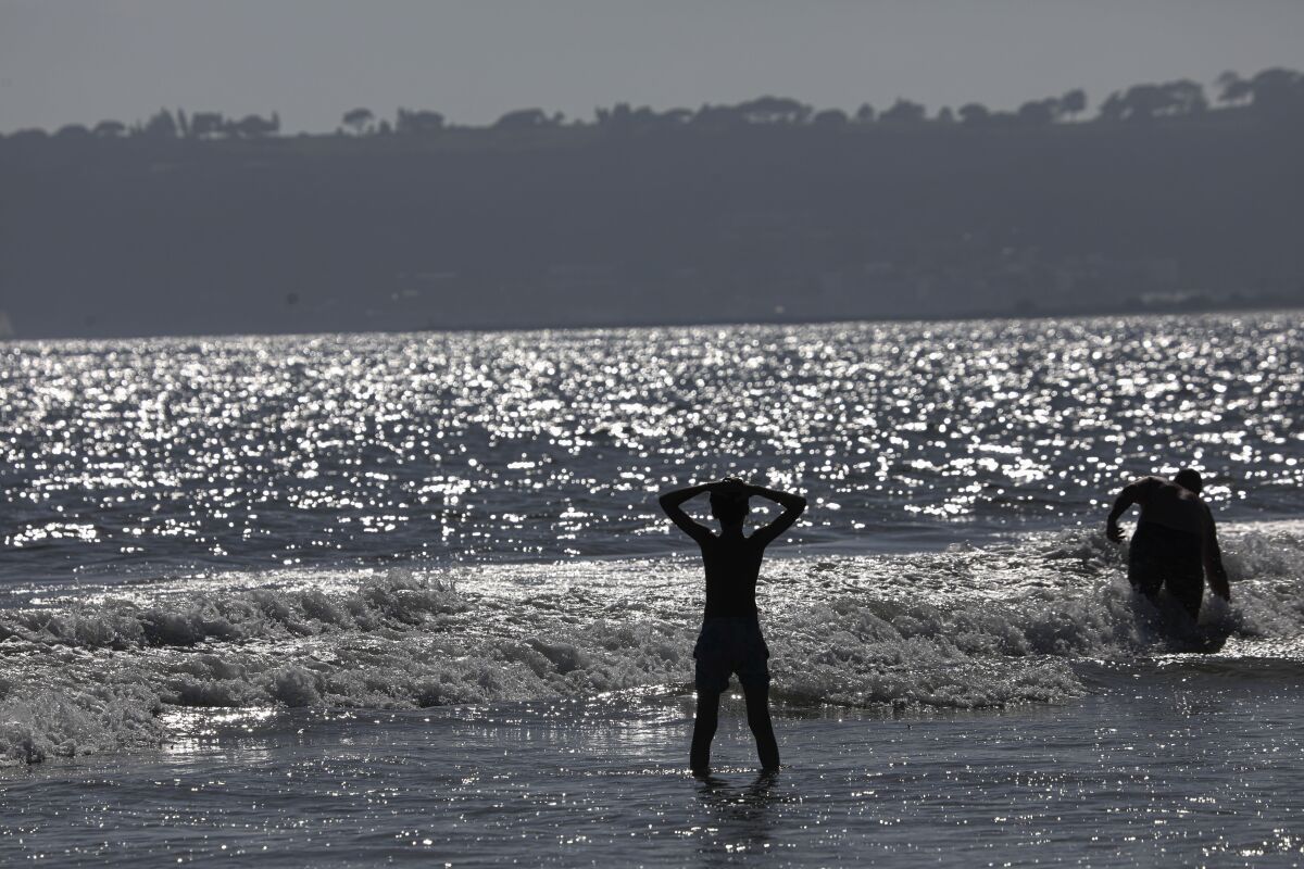 Beachgoers frolic along the sore and in the surf near the Hotel Del Coronado on June 29, 2022.