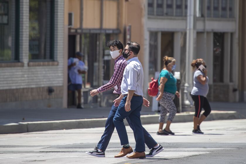  Pedestrians wearing masks cross Main Street on 4th Street in downtown Santa Ana.