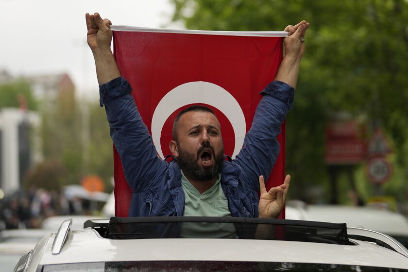 A supporter of the President Recep Tayyip Erdogan holding a Turkish flag shouts slogans outside AK Party offices in Istanbul, Turkey, Sunday, May 28, 2023. Erdogan takes lead in unofficial count in Turkey's presidential runoff. (AP Photo/Khalil Hamra)