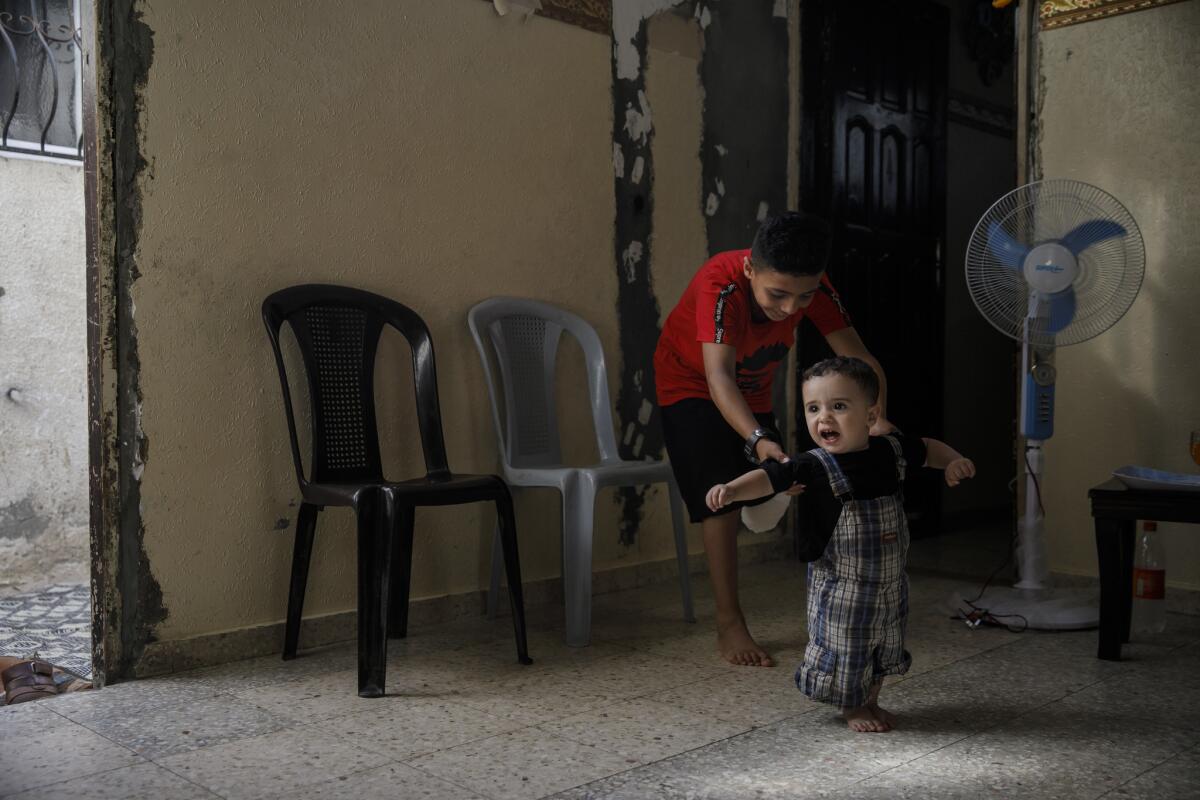 Abdel-Rahman Nofal helps his 1-year-old brother, Mustafa, walk. (Marcus Yam / Los Angeles Times)