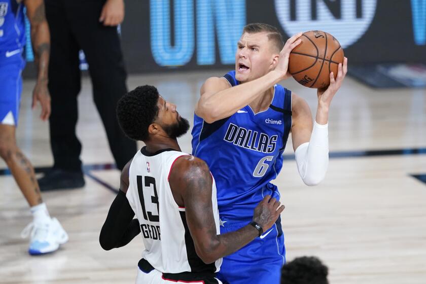 Dallas Mavericks' Kristaps Porzingis (6) is defended by Los Angeles Clippers' Paul George (13) during the first half of an NBA basketball first round playoff game Friday, Aug. 21, 2020, in Lake Buena Vista, Fla. (AP Photo/Ashley Landis, Pool)