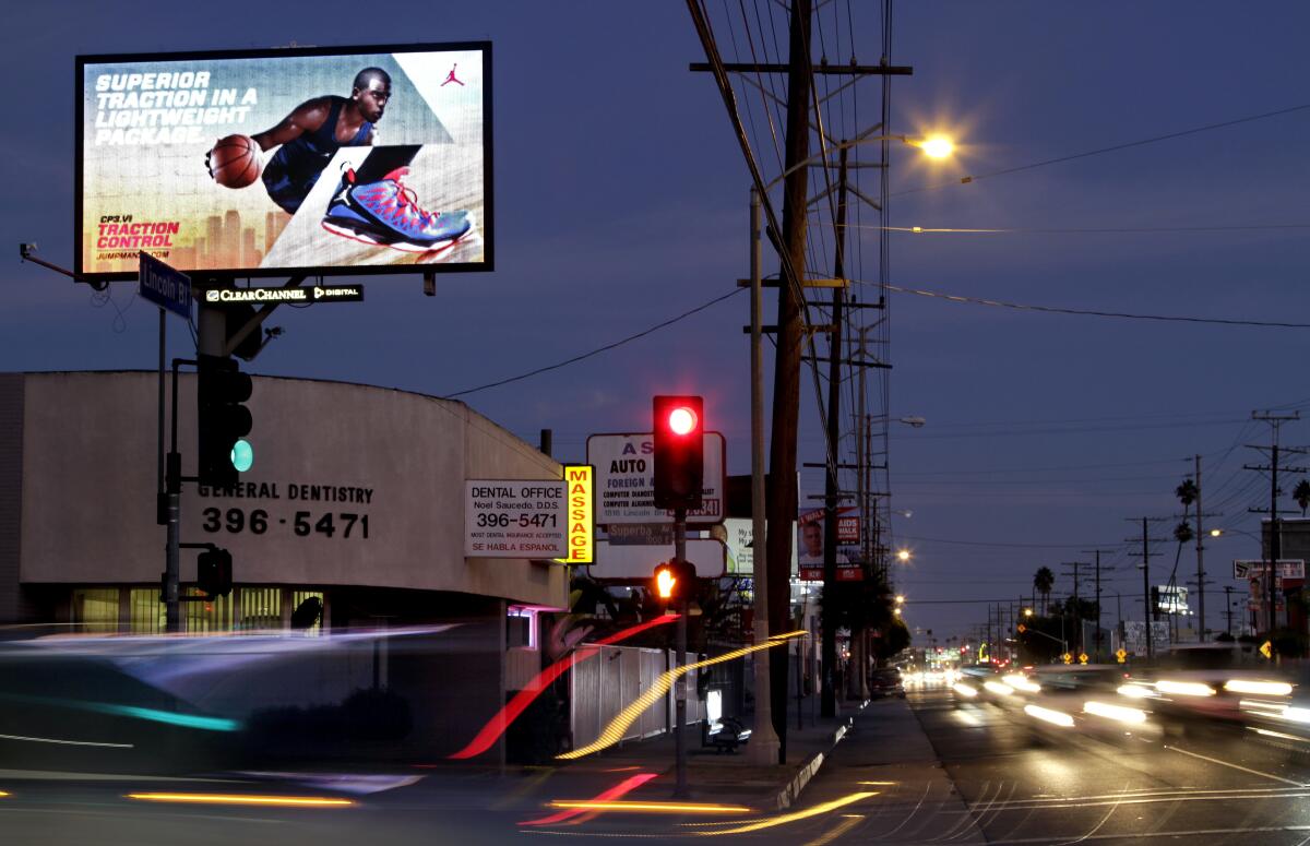 Digital billboard is lit up above a darkened street at night