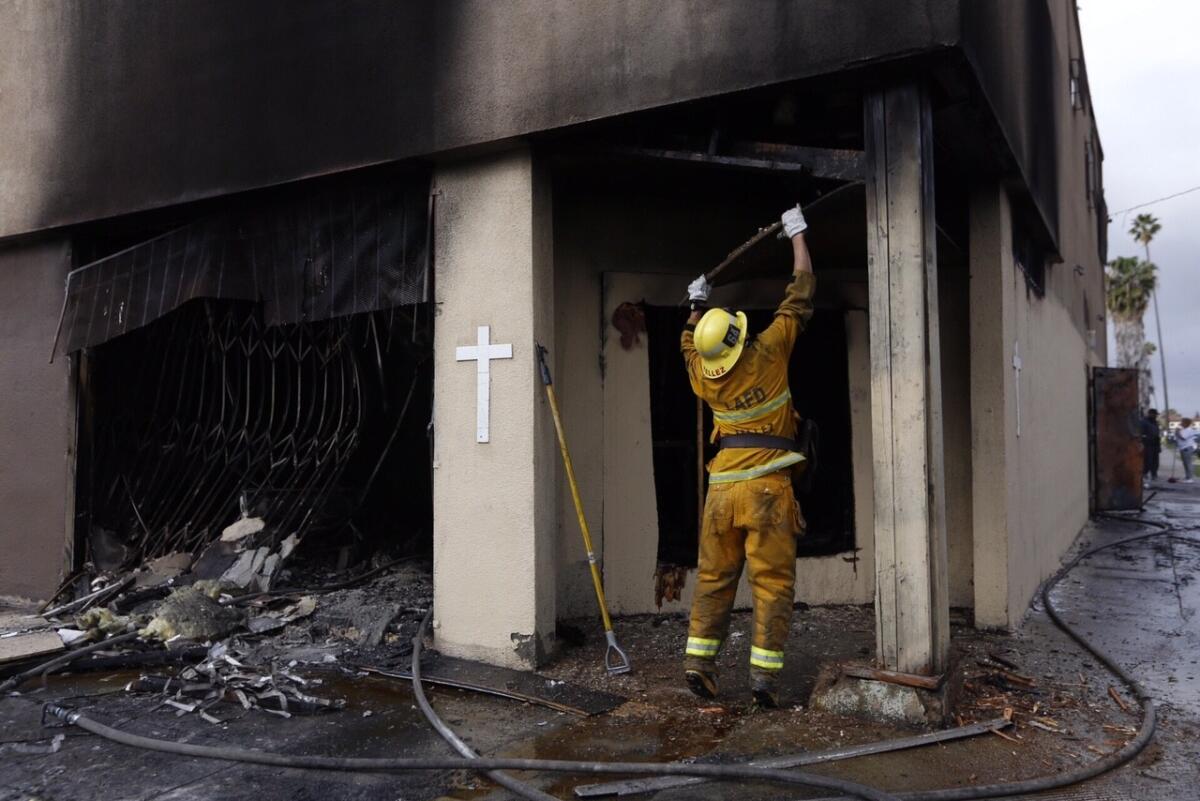 Los Angeles city firefighters mop-up after a greater-alarm fire at an abandoned church building in the South Los Angeles Monday morning.