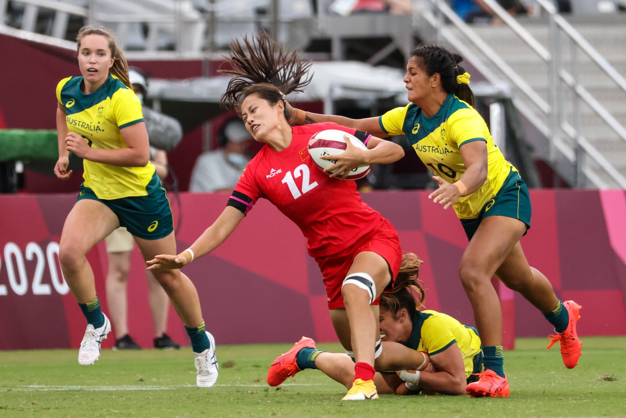 Team China's Hongting Ruan (12) struggles to outrun Team Australia's Sariah Paki (10) in the Women's Rugby Sevens.