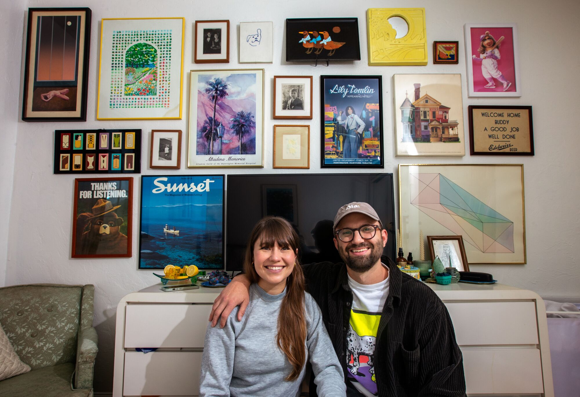 Amy Solomon and her boyfriend Greg Kestenbaum sitting together in front of a gallery wall.