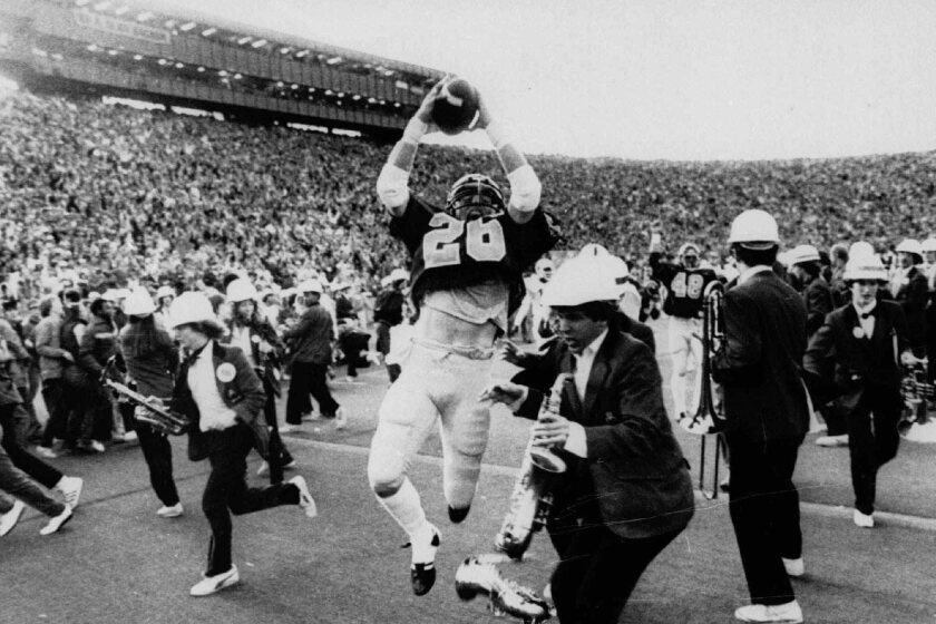 ** FILE ** California's Kevin Moen (26) leaps with the ball in the air after scoring Cal's winning touchdown while the Stanford band runs to get out of his way in Berkeley, Calif., in this Nov. 25, 1982 photo. When the Big Game rolls around each fall, Kevin Moen and Gary Tyrrell can't help being reminded about their roles in the wackiest four seconds in college football history. In 1982, Moen scored for California on the game–ending, five–lateral kickoff return known simply as The Play _ and Tyrrell was the Stanford band's trombone player who got leveled by Moen in the end zone. (Note: Tyrrell not pictured here.)(AP Photo/Oakland Tribune/Robert Stinnett)