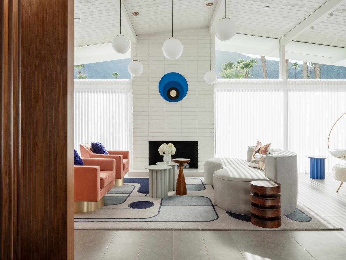 A living room with pink chairs and a white leather sofa.