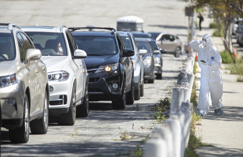 A line of cars next to a person in protective gear