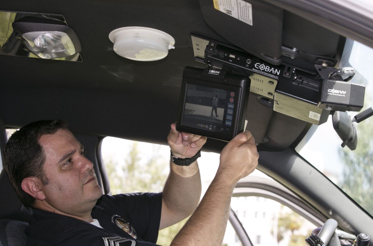 Los Angeles Police Sgt. Dan Gomez, a department expert on recording devices, shows a video display inside a patrol car with a camera pointed through the windshield at right, during a demonstration for media in Los Angeles in April 2014.