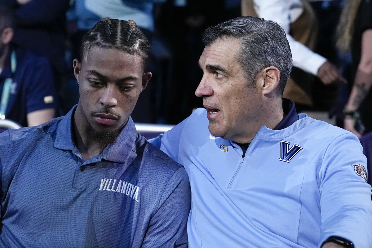 Injured Villanova guard Justin Moore sits with head coach Jay Wright before a college basketball game against Kansas in the semifinal round of the Men's Final Four NCAA tournament, Saturday, April 2, 2022, in New Orleans. (AP Photo/Brynn Anderson)