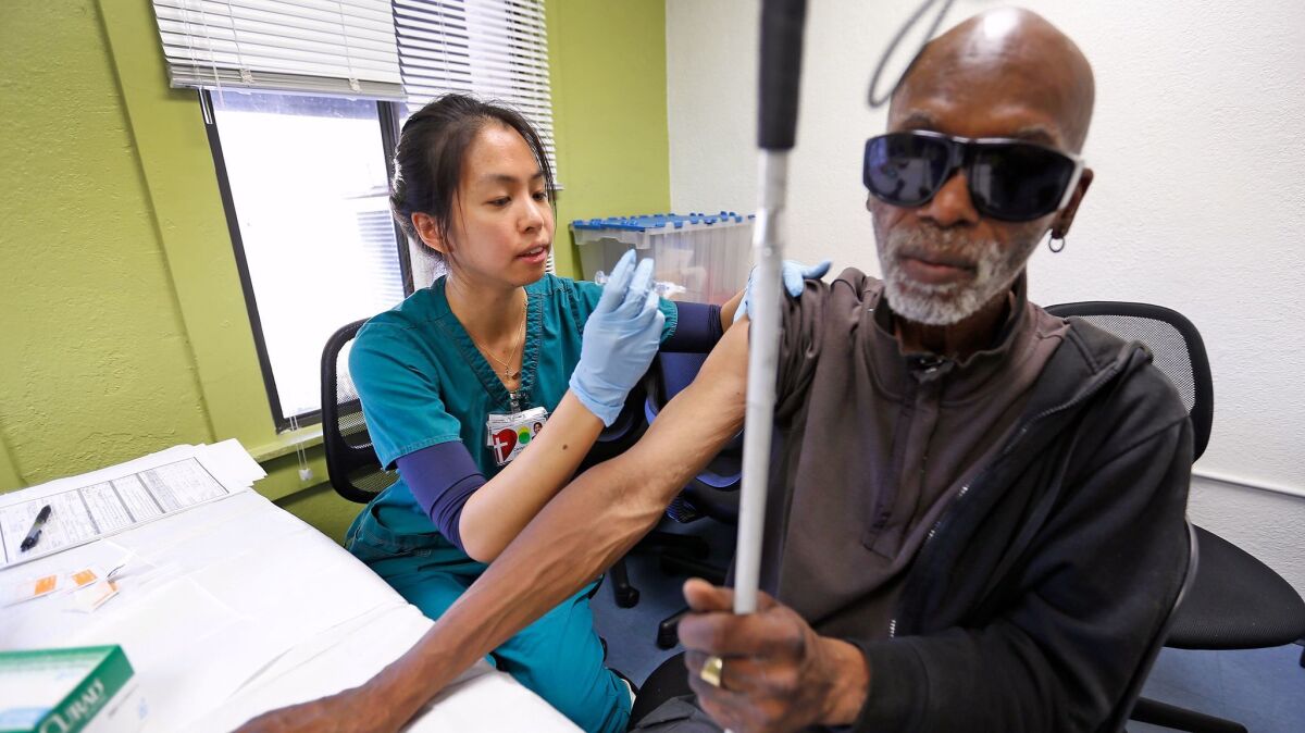 Carolyn Angela Chen, a nurse with Los Angeles Christian Health Centers, gives a free hepatitis A vaccination to Marcel Anthony, 63, at Joshua House Clinic on skid row in L.A.