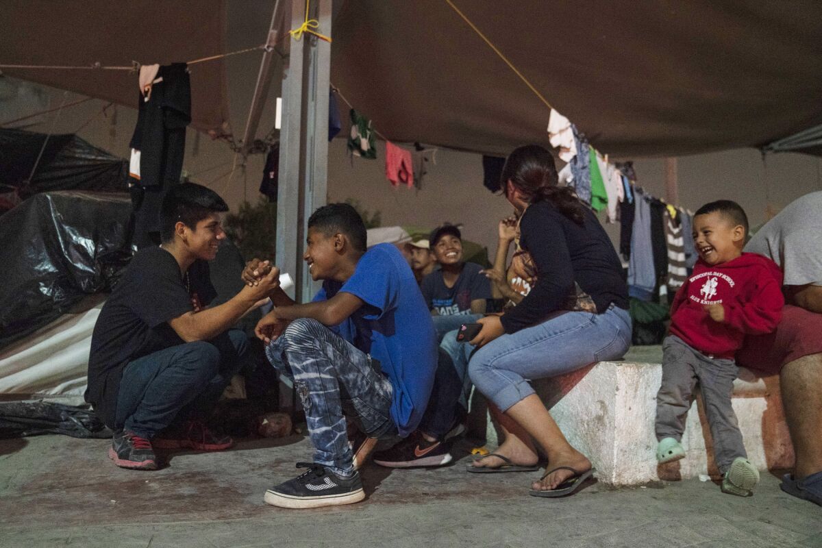 Adolescentes centroamericanos que buscan asilo juegan en un campamento donde viven cerca del Puente Internacional Gateway.