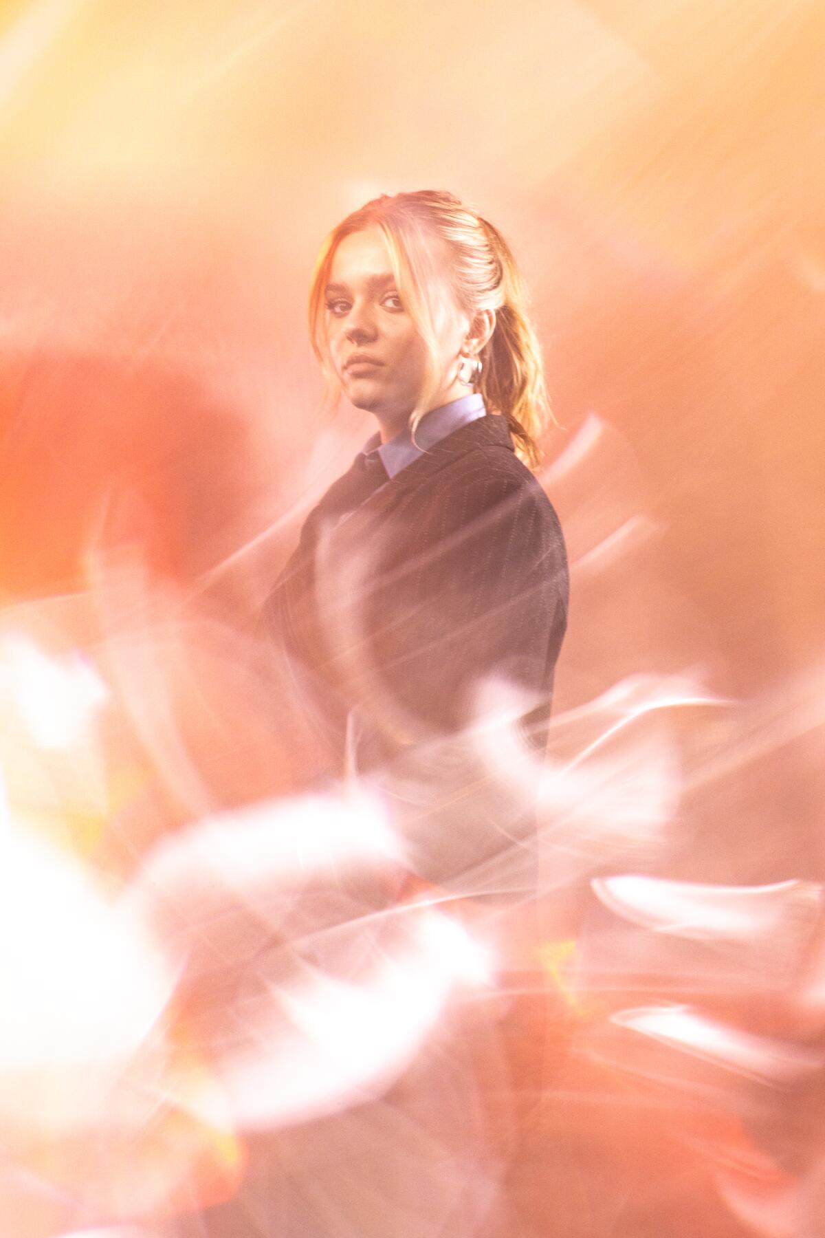 A woman stands with light streaks in the foreground.