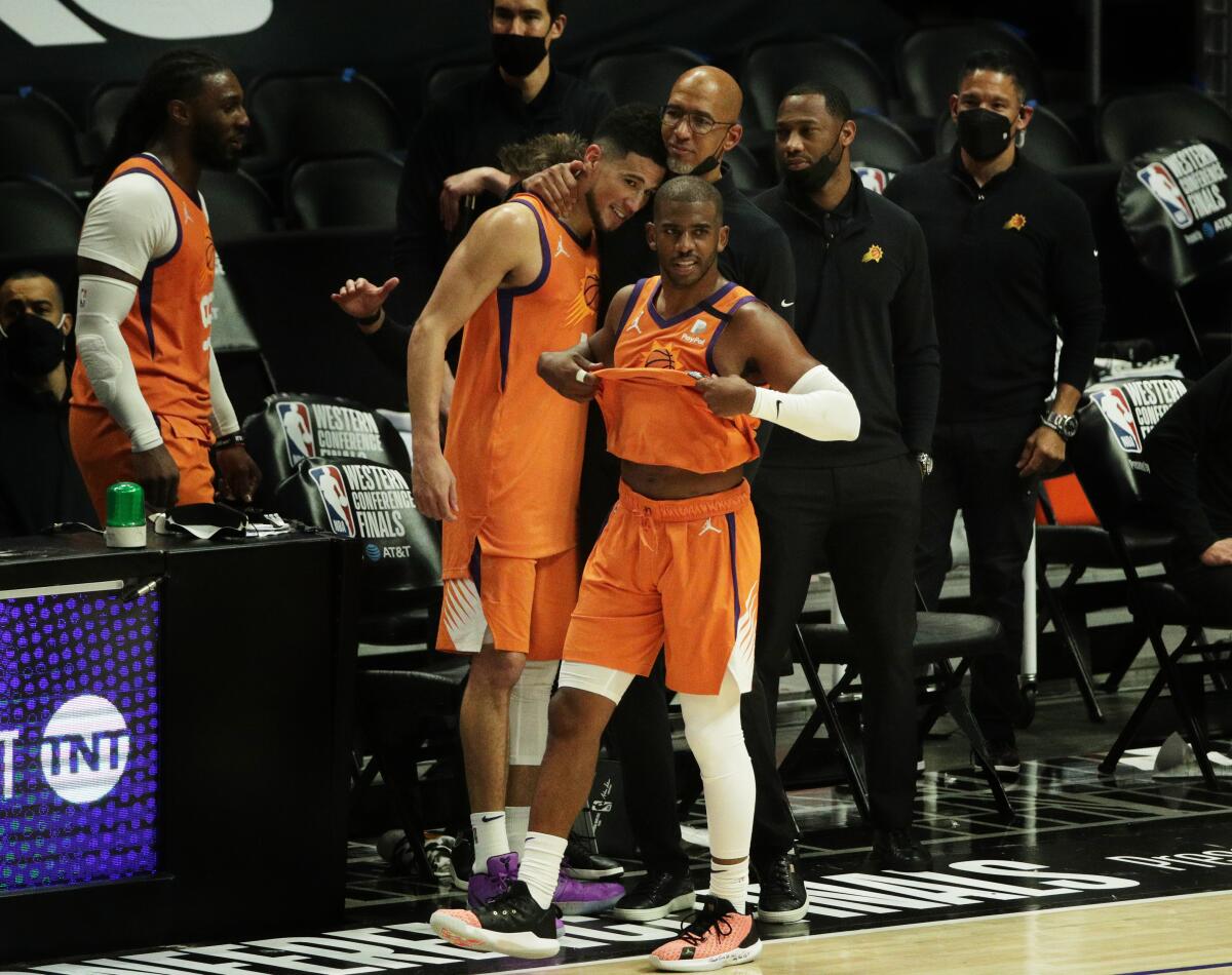 Suns Coach Monty Williams hugs Suns guard Devin Booker (1) as Suns guard Chris Paul watches the final seconds of Game 6.