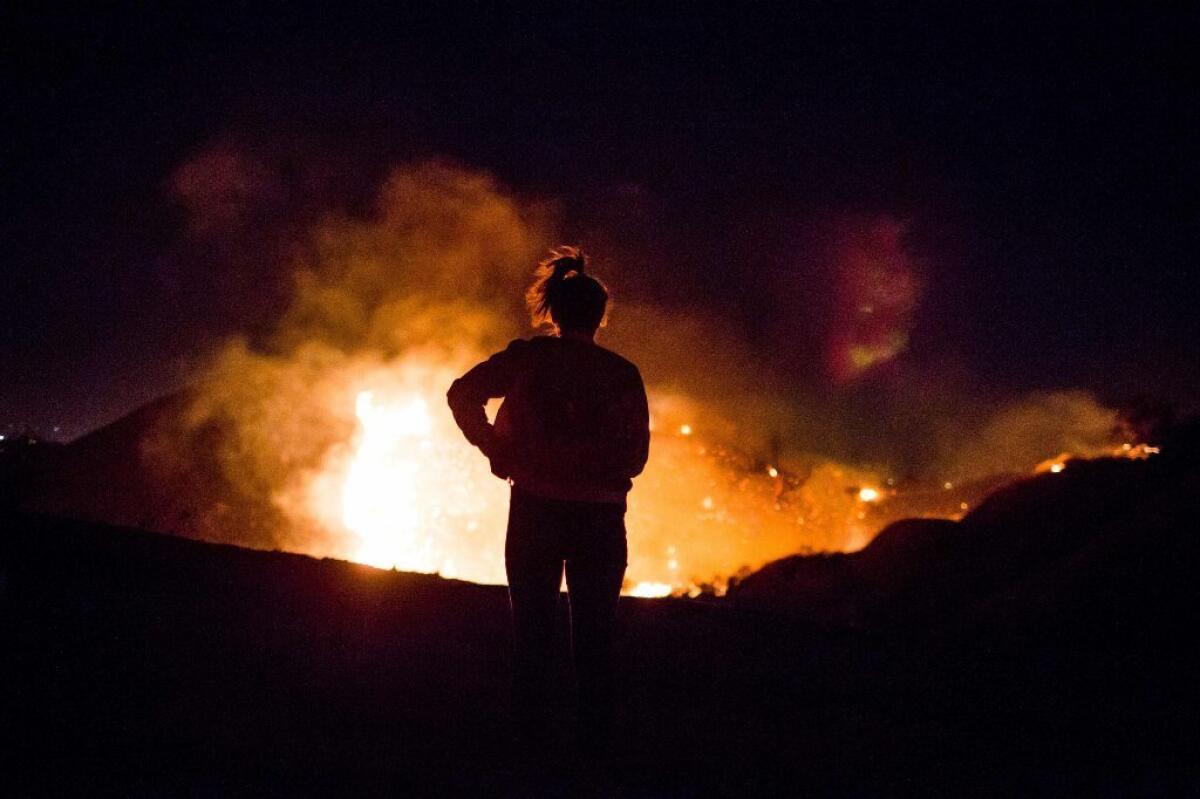A resident watches as the Creek fire burns along a hillside near homes in Shadow Hills.