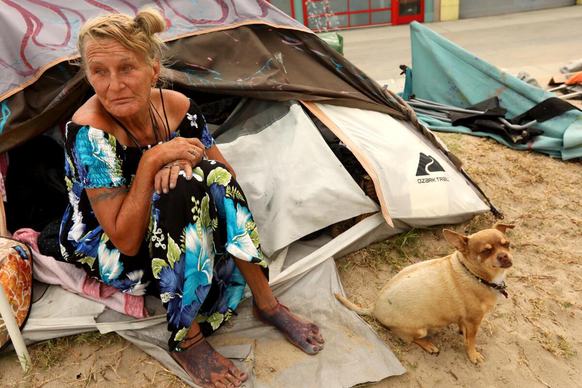 Teresa Robles, 63, and her dog Notcho sit outside their tent along Ocean Front Walk in Venice.