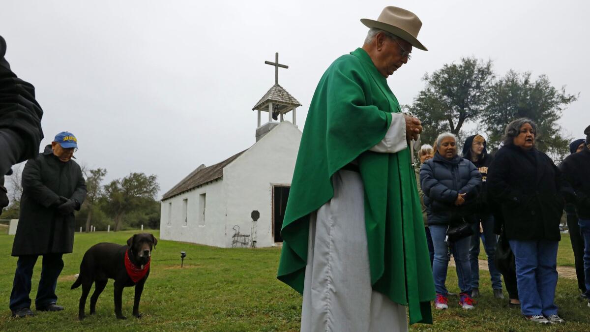 Father Roy Snipes leads a prayer at La Lomita chapel Friday morning as part of a vigil to try to save the 19th century building in Mission, Texas, from being blocked off by a border fence.