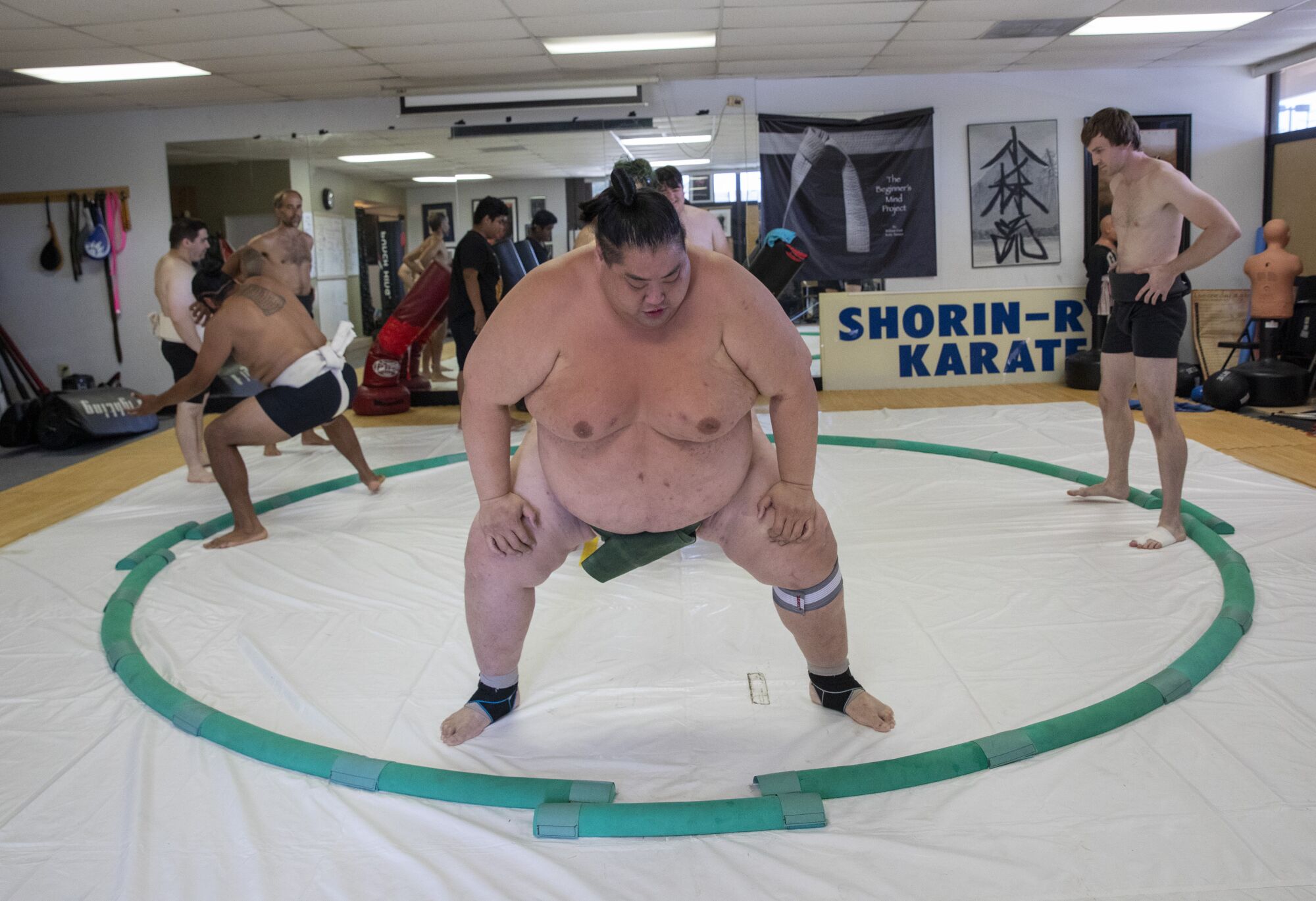 Ryuichi Yamamoto, a former Japanese professional sumo champion, guides the correct technique