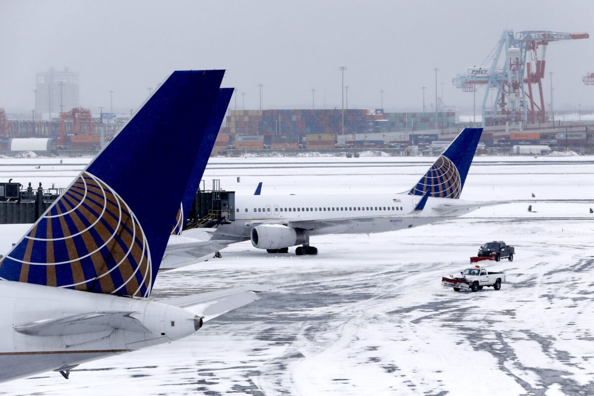 Trucks pushing plows clean up the tarmac area as United Airlines planes board at Newark Liberty International Airport following an overnight snowstorm, which forced the cancellation of most flights in and out of the airport, Tuesday, Jan. 27, 2015, in Newark, N.J. A university study says a rule that fines airlines for stranding passengers on the tarmac leads to more delays.