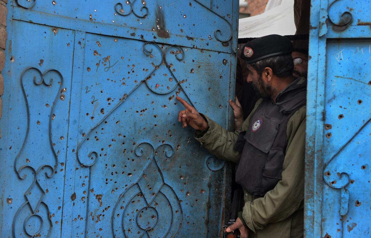 A Pakistani police officer looks at a shrapnel-riddled gate damaged in a suicide bombing on the outskirts of Peshawar, Pakistan, on Monday.