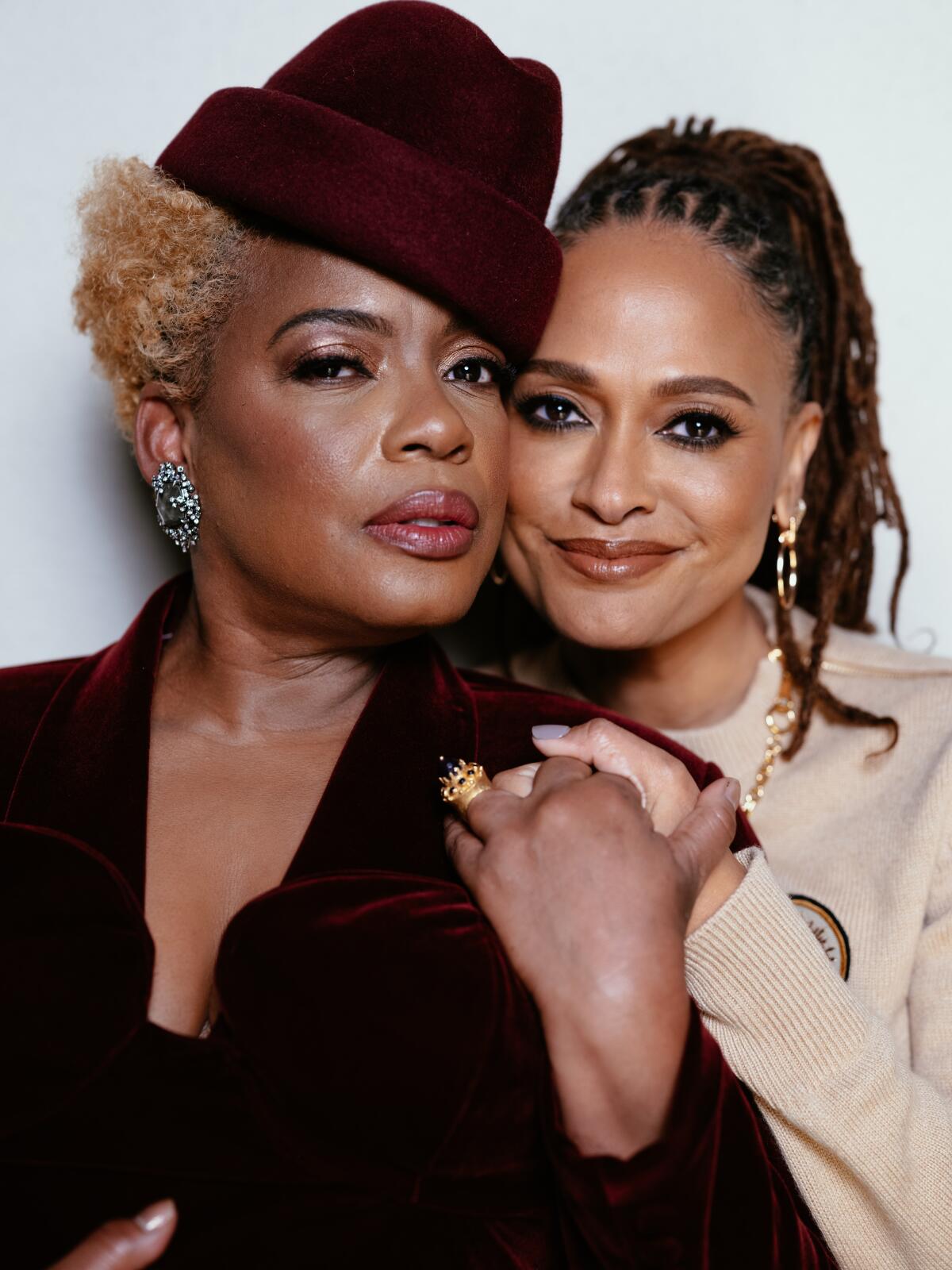 Aunjanue Ellis-Taylor and Ava DuVernay stand cheek to cheek, hands clasped together.