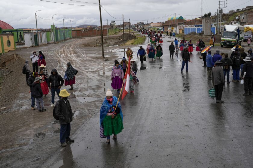 Los residentes caminan a lo largo de una barricada colocada por manifestantes que piden la renuncia de la presidenta Dina Boluarte y la disolución del Congreso, en Acora, en el sur de Perú, el domingo 29 de enero de 2023. (Foto AP/Rodrigo Abd)