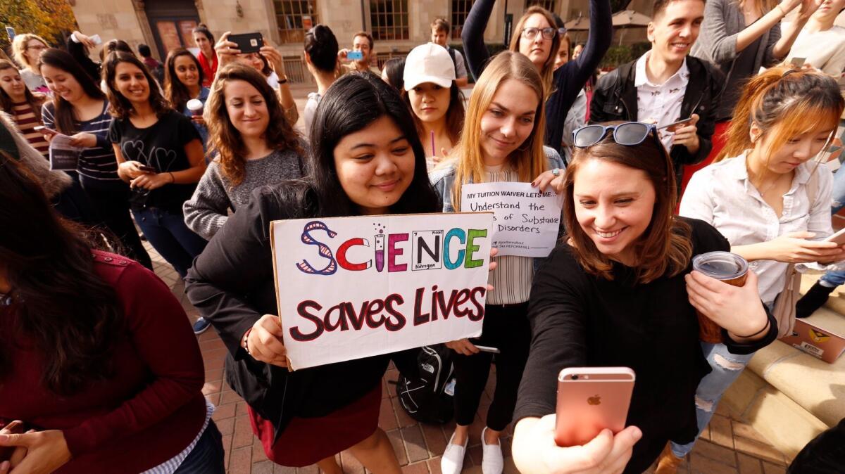 USC graduate students Mariel Bello, Nina Christie and Alyssa Morris, left to right, pose for a selfie to post online and forward to their congressman as they joined national protests against the GOP tax bill, which they say will significantly boost their taxes.