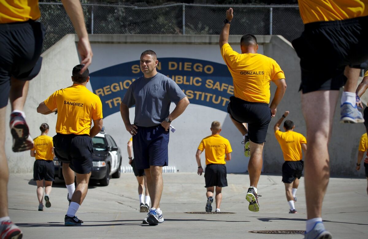 A recruit training officer watches San Diego police and sheriff’s recruits during physical training in this 2016 file photo.