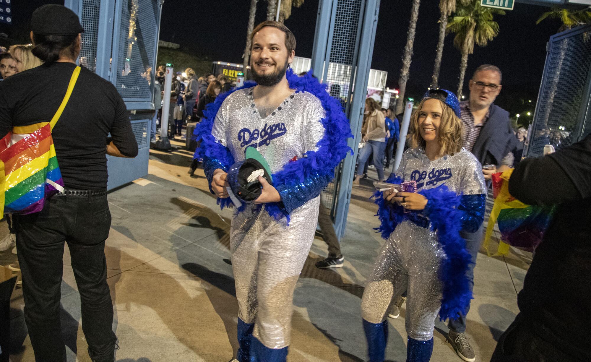 A man and a woman wear spangled Dodger uniforms and matching blue feather boas.