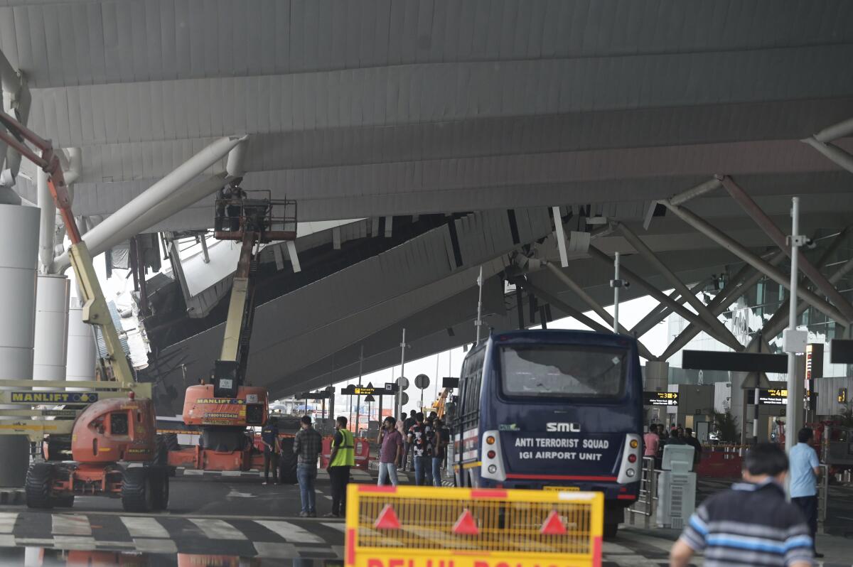 A crew inspects damage from a collapsed airport canopy. 