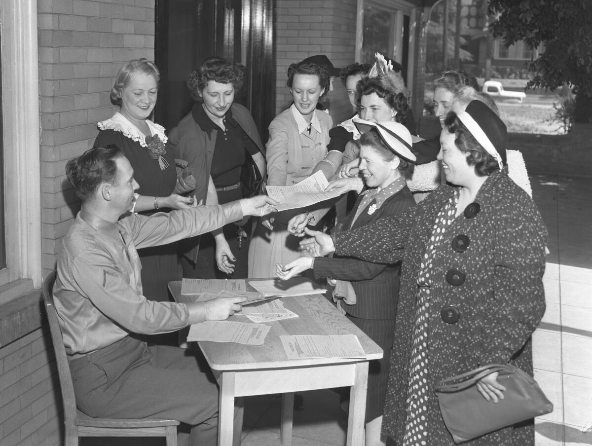 A man hands out applications for enlistment in the Women's Army Auxiliary Corps to several women.