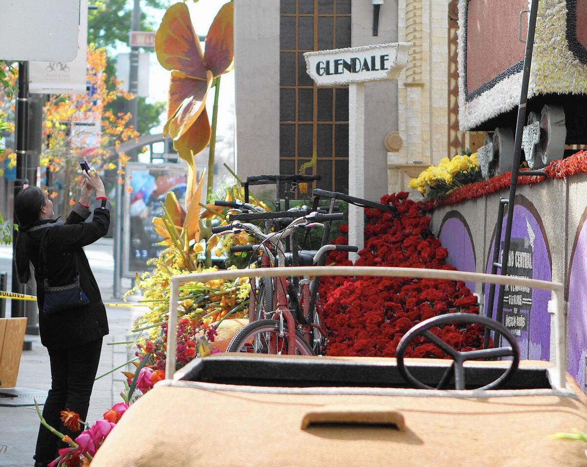 A woman takes a photo of a detail on the Glendale Rose Parade float, which was parked in front of the Alex Theatre on Monday.
