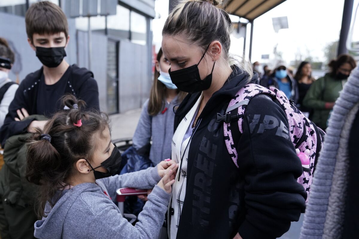 A woman from Ukraine stands with her children before crossing into the United States, Thursday, March 10, 2022, in Tijuana, Mexico. U.S. authorities allowed the woman and her three children to seek asylum Thursday, a reversal from a day earlier when she was denied entry under the Biden administration's sweeping restrictions for seeking humanitarian protections. (AP Photo/Gregory Bull)