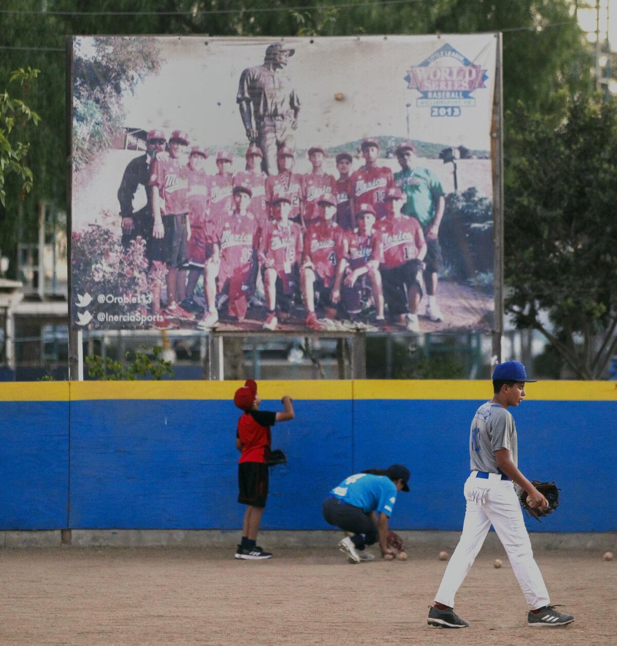 Municipal de Tijuana team members in front of a picture of the 2013 Tijuana Little League team that went to the Little League World Series.