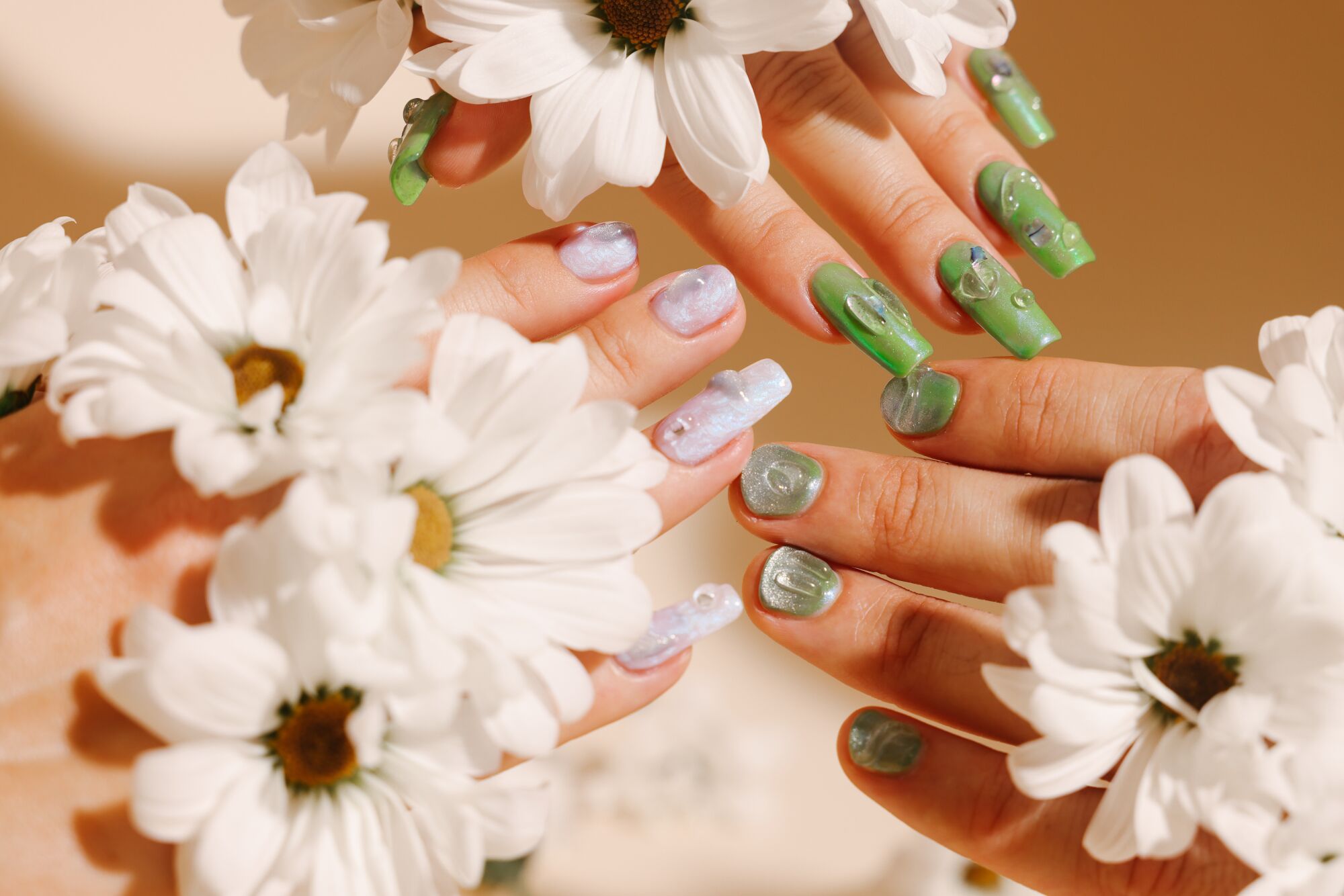 Hands with painted nails reaching into the frame, holding white flowers.
