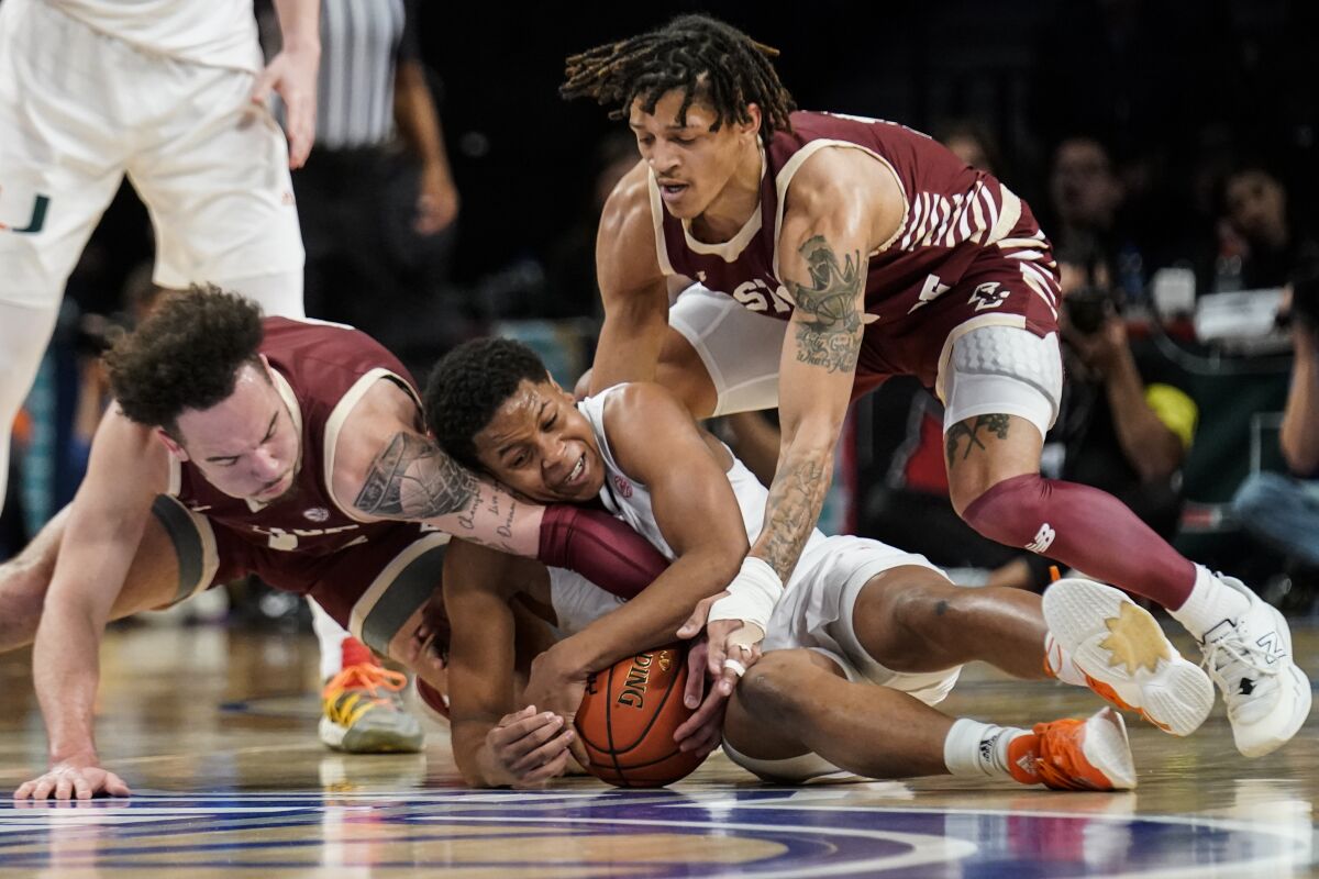 Miami's Charlie Moore, center, Boston College's Jaeden Zackery, left, and Makai Ashton-Langford, right, battle for the ball in the first half of an NCAA college basketball game during quarterfinals of the Atlantic Coast Conference tournament, Thursday, March 10, 2022, in New York. (AP Photo/John Minchillo)