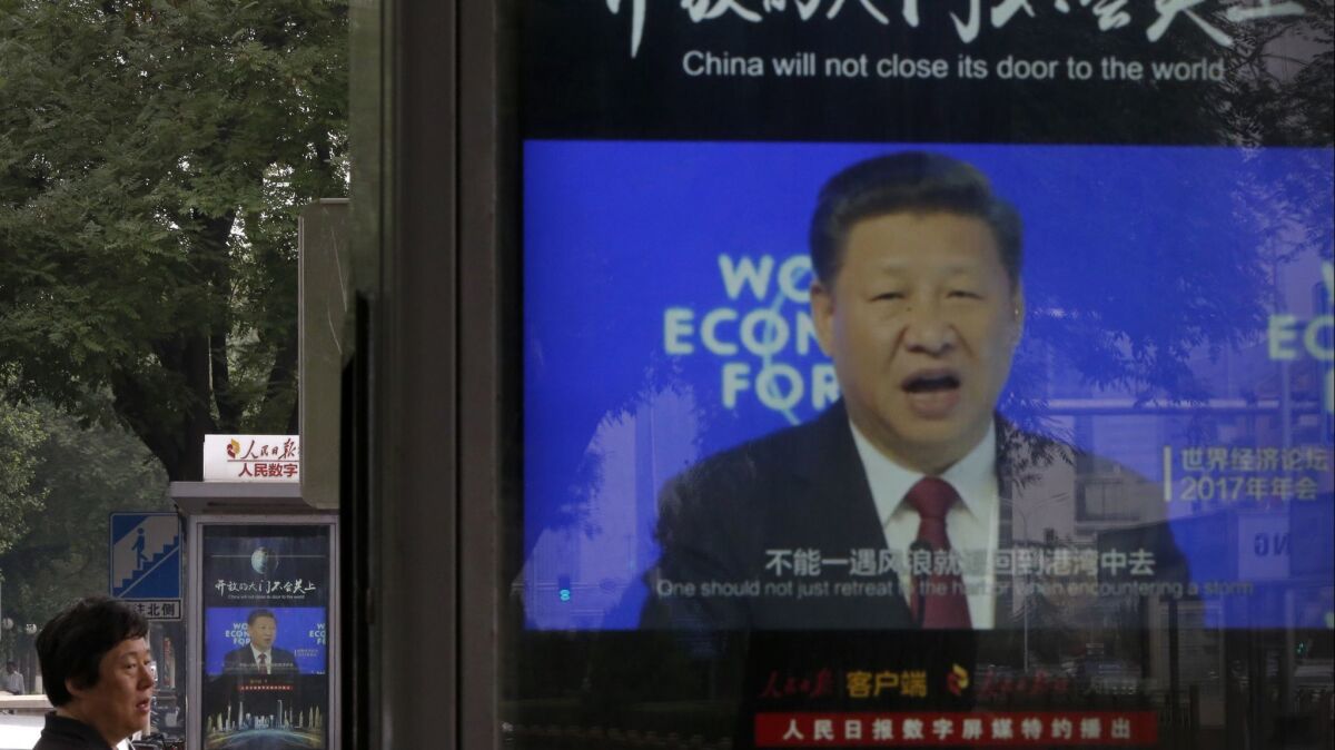 A man walks past electronic display panels in Beijing showing video footage of Chinese President Xi Jinping addressing the World Economy Forum.