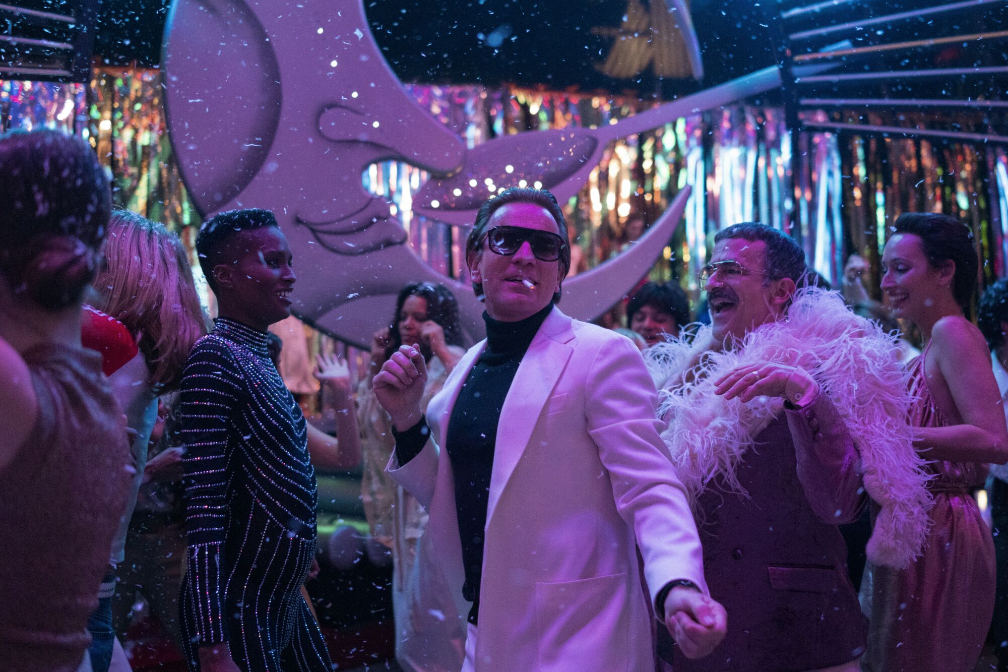 Several well-dressed people, with Ewan McGregor as Halston in the center, dancing inside Studio 54 in "Halston."