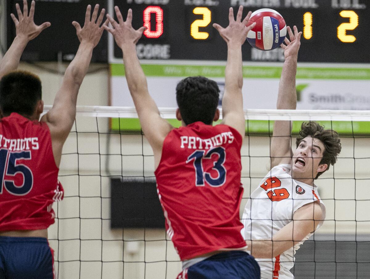 Huntington Beach's Ben Bray hits into Beckman's Noah Huang, left, and Ryan Graves in a nonleague boys' volleyball match.