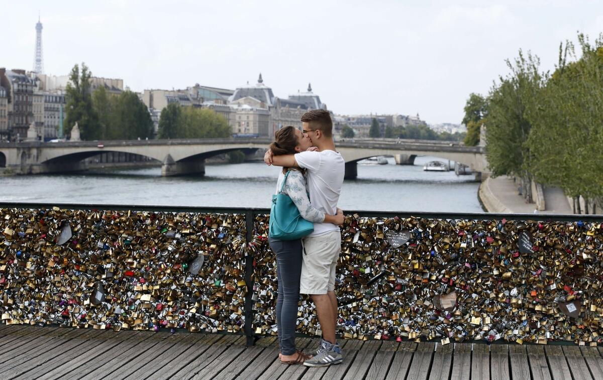 A couple kisses on the Pont des Arts in Paris. Lovers have attached thousands of "Love locks" to the bridge since 2008. Their secrets are safe. Are yours?