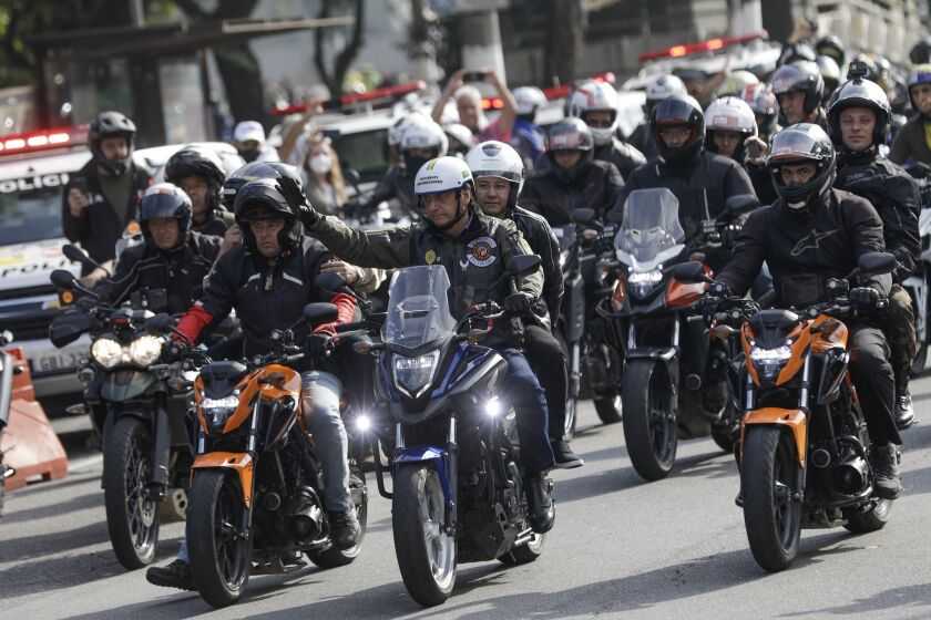 Brazil's President Jair Bolsonaro, center, waves as he leads a caravan of motorcycle enthusiasts following him through the streets of the city, in a show of support for Bolsonaro, in Sao Paulo, Brazil, Saturday, June 12, 2021. (AP Photo/Marcelo Chello)