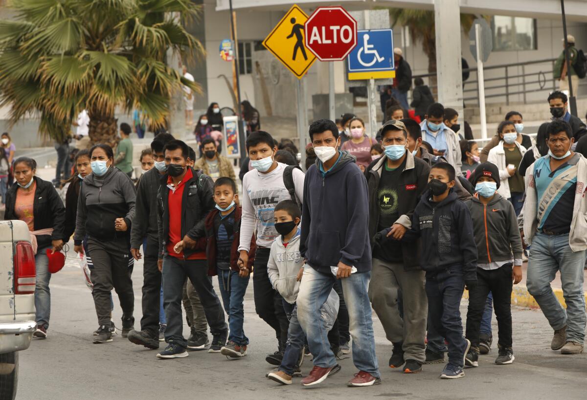 Men, women and children walk on a street in Reynoso, Mexico.