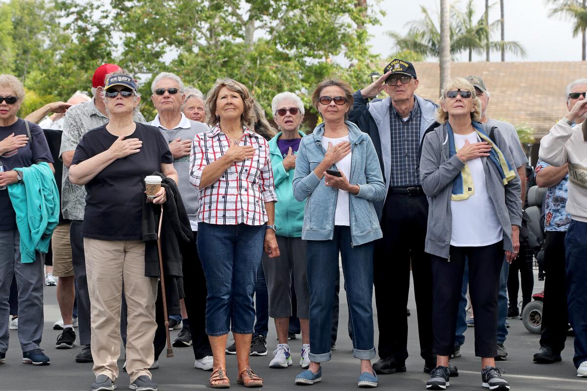 Residents and military veterans look on during a flag-raising ceremony on Wednesday morning in Huntington Beach.