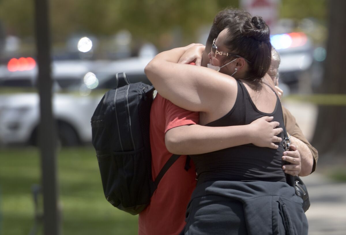 A family member hugs a student after a fatal shooting at Washington Middle School in Albuquerque, N.M., Friday, Aug. 13, 2021. New Mexico authorities say one student was killed and another was taken into custody following a shooting at a middle school near downtown Albuquerque during the lunch hour Friday. (Robert Browman/The Albuquerque Journal via AP)
