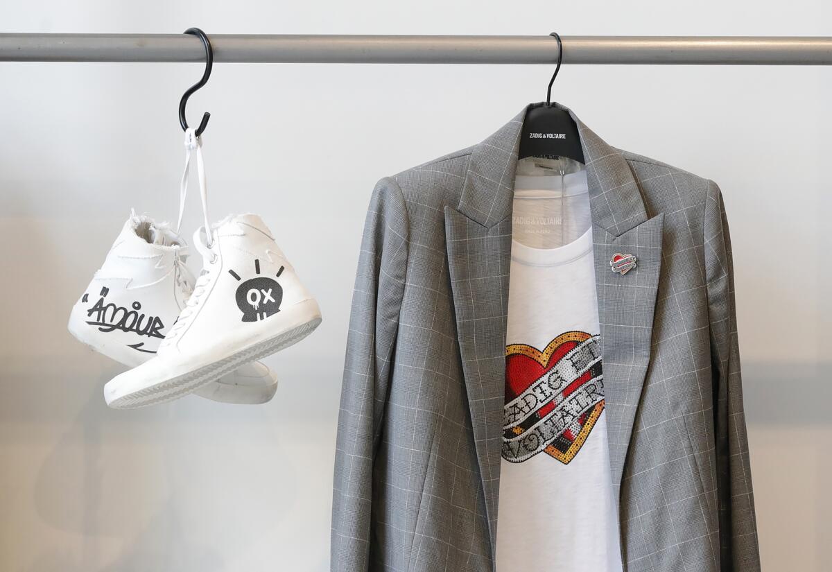 A pair of high top sneakers with Jormi Graterol graffiti art and sports jacket on display.