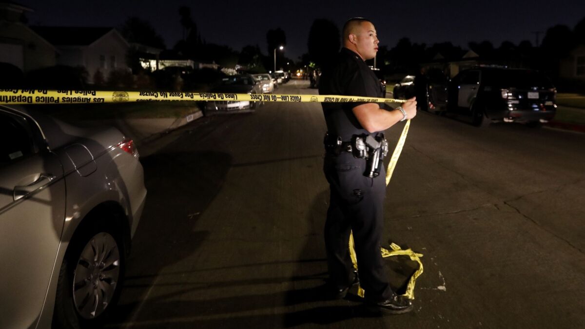 Los Angeles Police Officer Moberg moves crime tape to allow an LAPD vehicle closer to the crime scene.