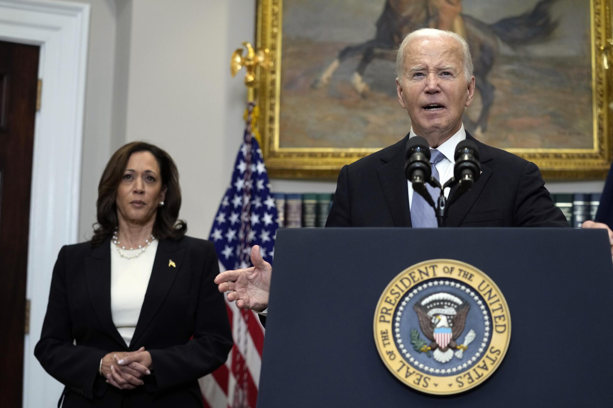 President Biden speaks from the Roosevelt Room with Kamala Harris behind and to the side of him.