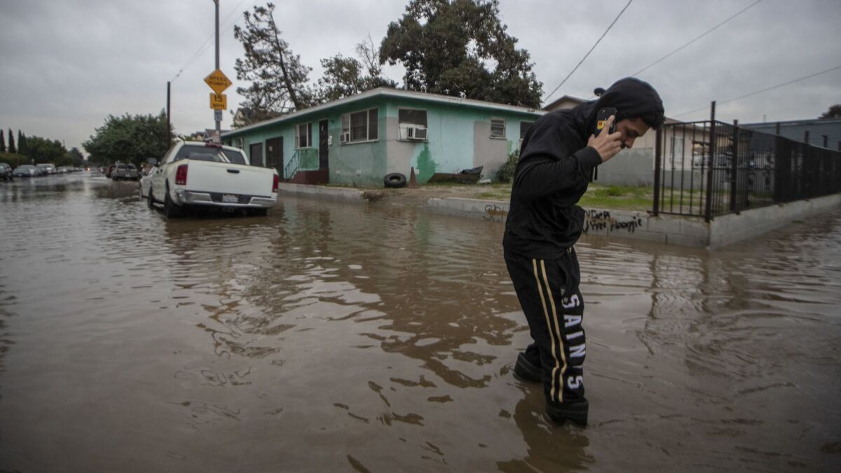 Justin Ibarra crosses a flooded intersectoin at 56th and Main Streets as LADWP crews work to stem the flow of water from a water main break in South Los Angeles.
