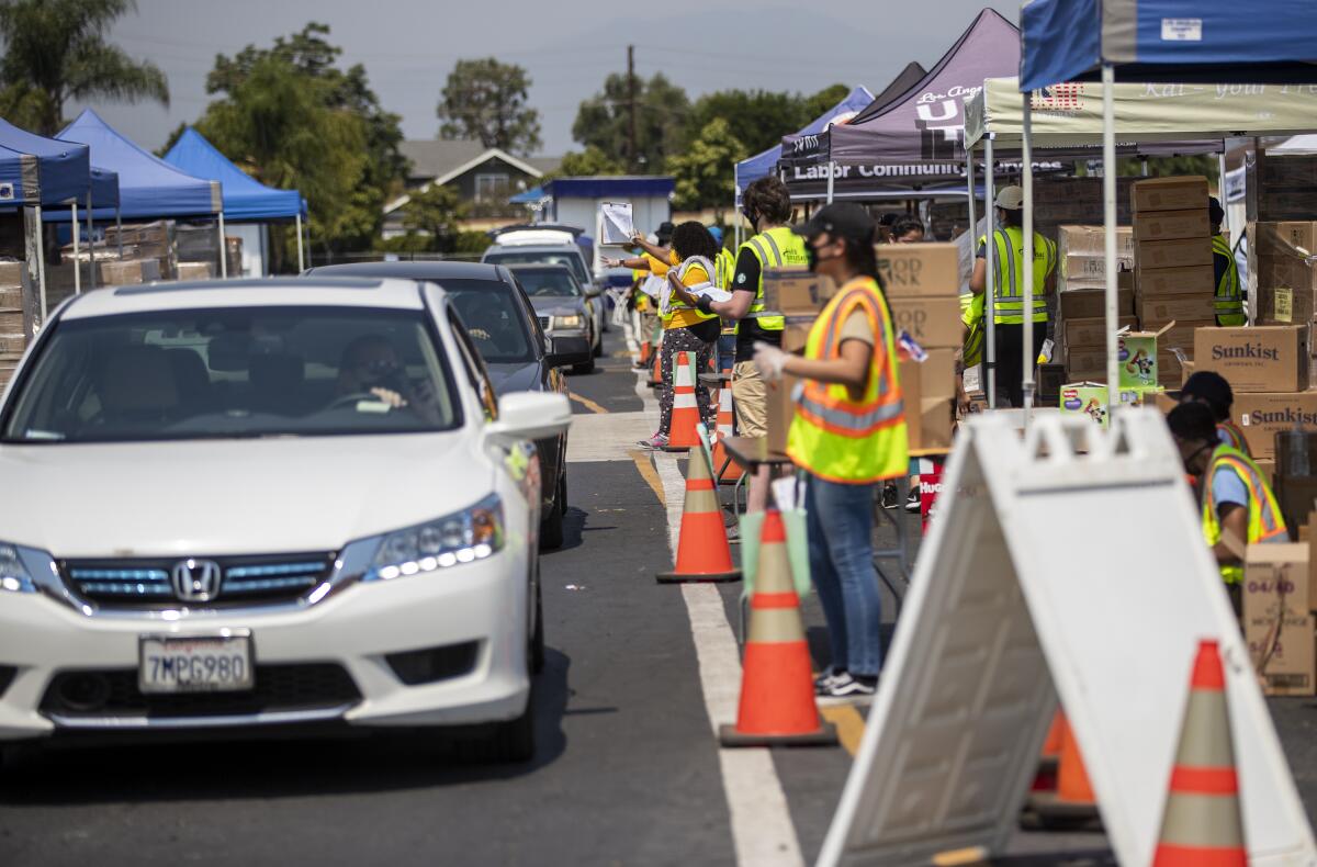 Cars are lined up to collect boxes of food at a food bank in Pomona in August. (Gina Ferazzi / Los Angeles Times)