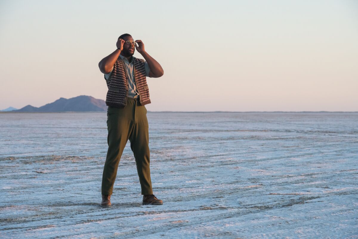 A man in a vest and glasses in a desert